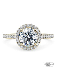 The Aphrodite halo engagement ring with a round-cut diamond in 18k yellow gold. The ring features a Castle setting with a total diamond weight of approx. 0.31ct.