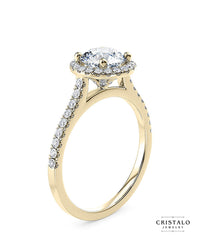 An exquisite Aphrodite halo ring, radiating elegance and warmth with a brilliant round diamond on an 18k yellow gold band.