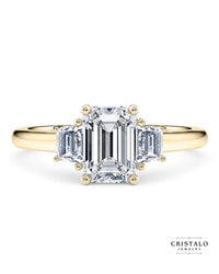 The Imperia Trilogy engagement ring with three step-cut emerald diamonds in 18k yellow gold. The ring has a total carat weight of 0.43ct and a vintage design.