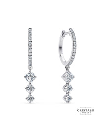 An elegant pair of Lyra earrings, diamond-dusted hoops hung with three linked diamonds, casting a celestial spell wherever they go.